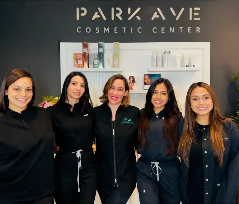 The Park Ave Cosmetic Center team in front of the studio sign